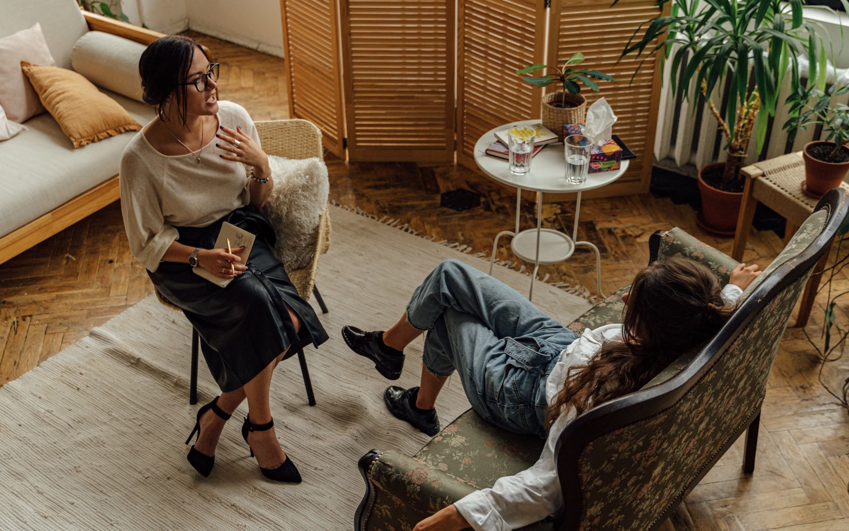 A therapist and client talking in a warm, sunlit living room