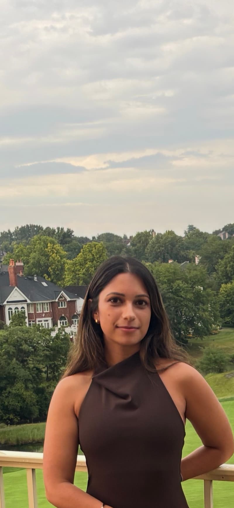 Asha Kanadia on a balcony overlooking trees and a fairway